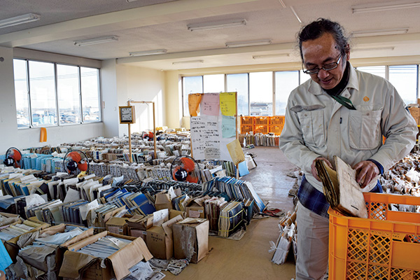 常総市行政文書保全指導員の林貴史さん　水損した約3500点の文書が並ぶ第1分庁舎3階フロアにて